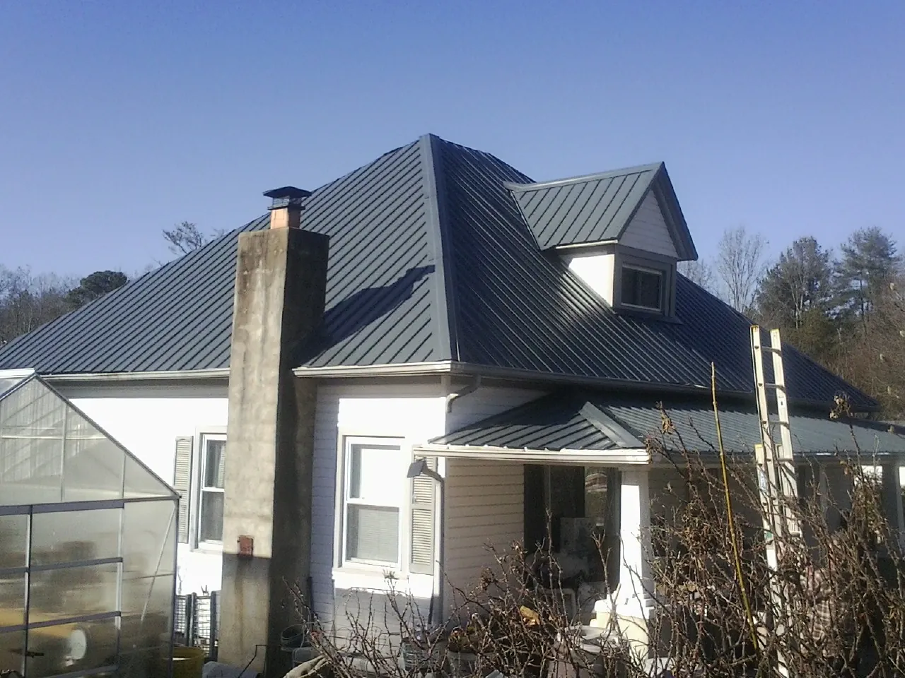 Dark blue standing seam metal roof on a white farmhouse with dormer — Slate & Tile Roof Repair by Roofing Brothers in Gruetli Laager