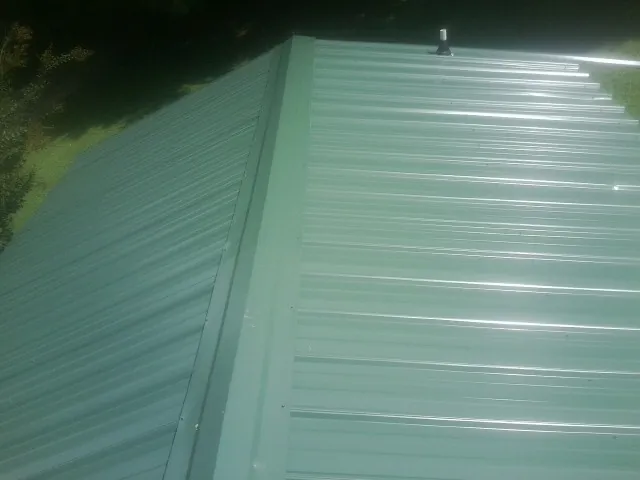 New green metal panels meeting at the ridge of a roof — Flat Roof Repair work by our crew in Gruetli Laager