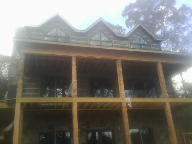 Dormers and porch framing on a large log home under construction — Roof Coating work by our crew in Gruetli Laager