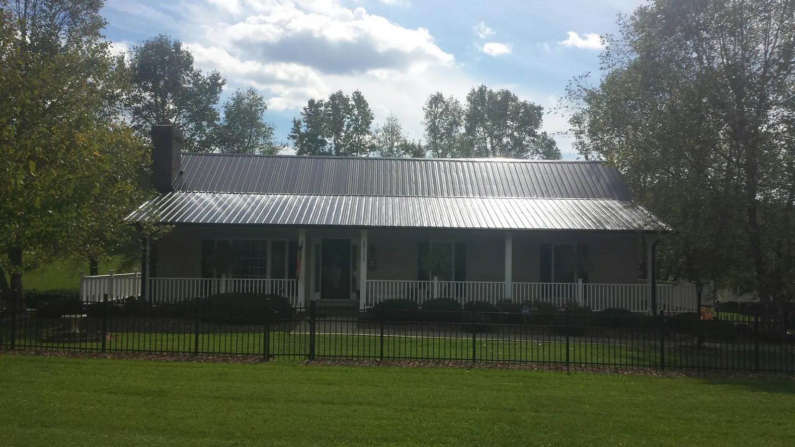Gray metal roof on a brick ranch with a full width front porch — Gutter Guard Installation work by our crew in Gruetli Laager