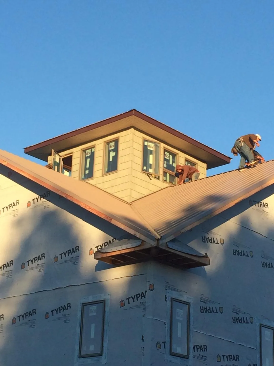 Roofers working around a rooftop cupola on a new metal roof at sunset — Roof Waterproofing in Gruetli Laager by Roofing Brothers